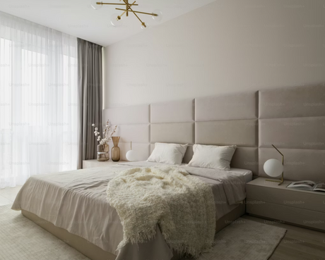 Well-dressed bed in a bright modern bedroom with upholstered headboard and neutral furnishings.
