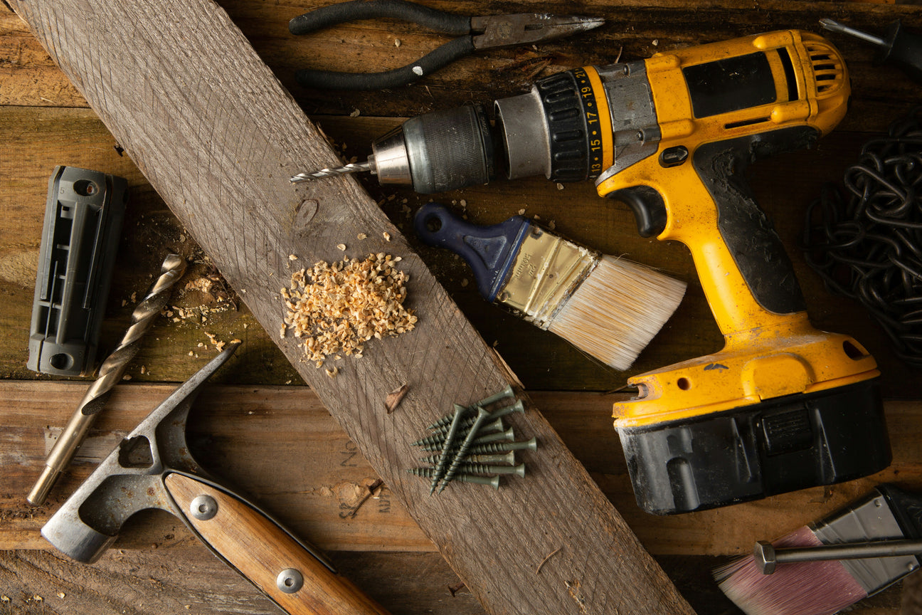Hardware tools and power drill on a wooden workbench for DIY, home improvement and repair projects.